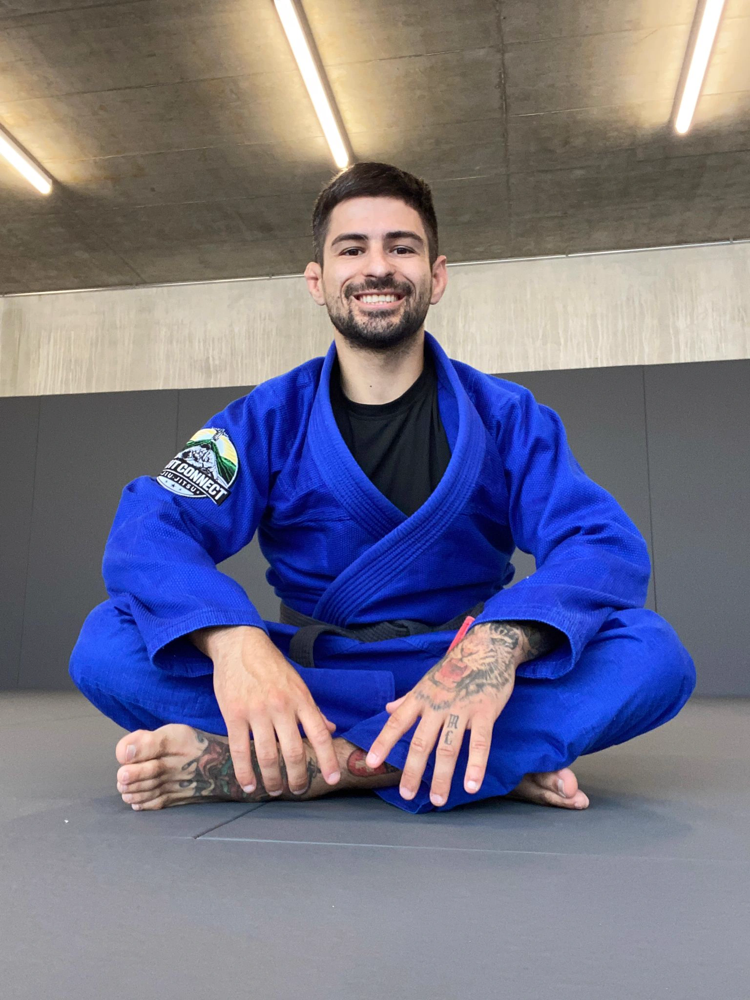 Frederico Gutzwiller, ceinture noire de jiu-jitsu, assis sur le tatami de Fight Connect en kimono bleu.